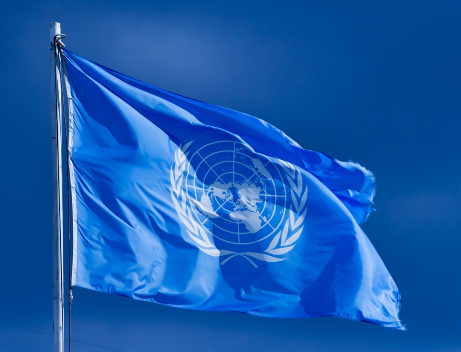 A United Nations flag flying against a background of clear, blue sky.