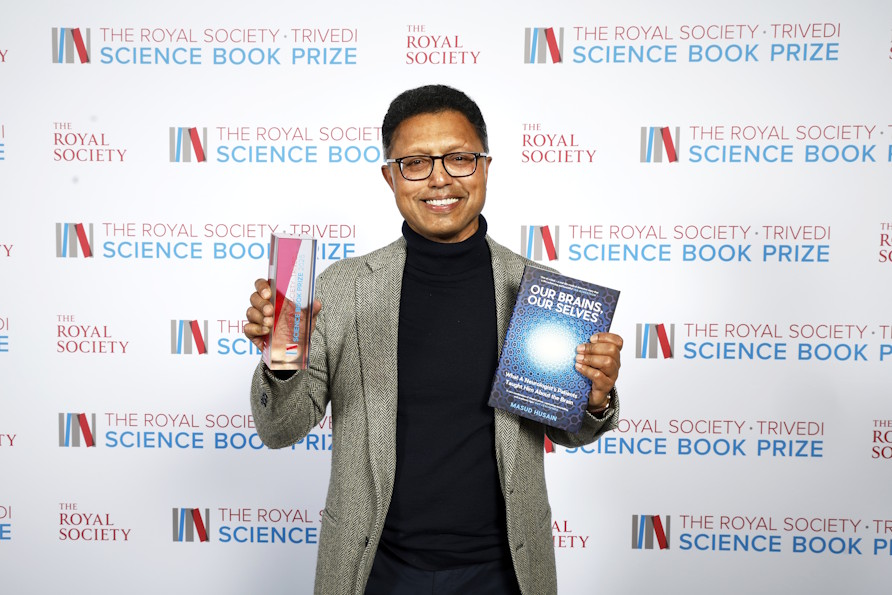 Winner Masud Husain holding the Science Book Prize trophy and his book "Our Brains, Our Selves"