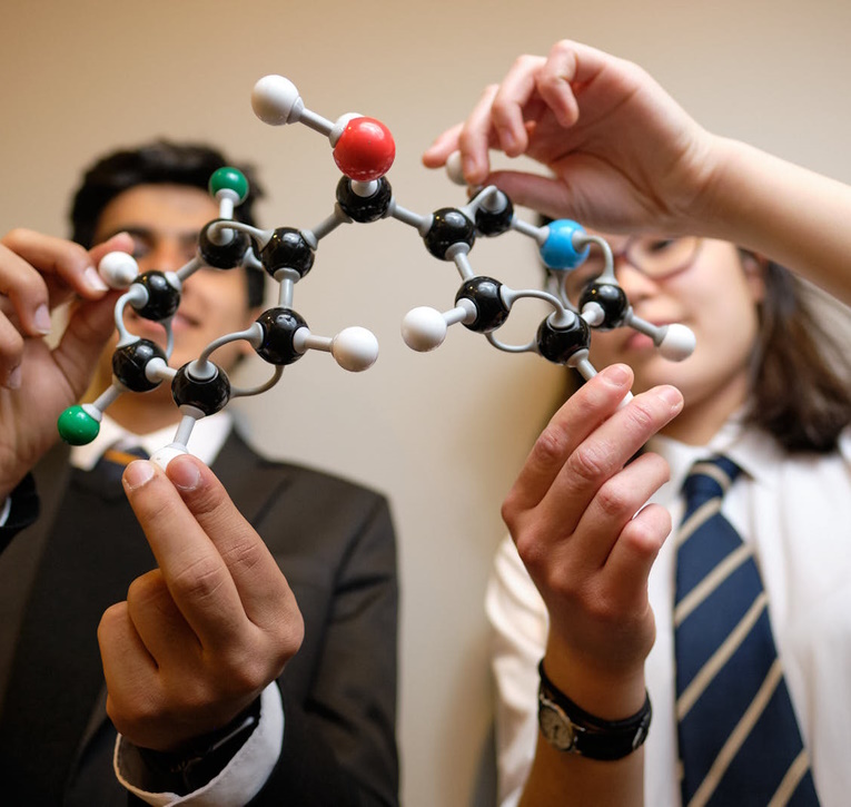Two school children are handling a model of a molecular structure