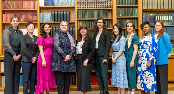 10 women stand in front of a bookcase