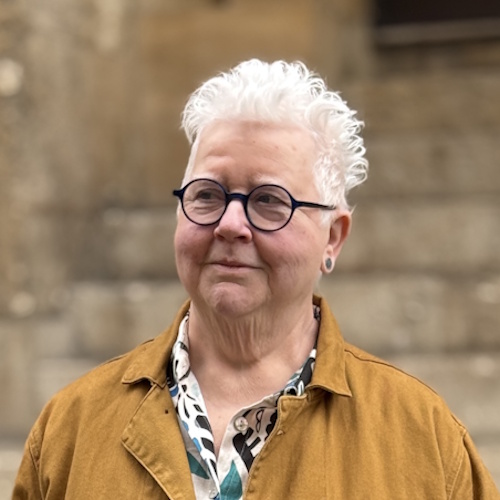 Val McDermid wearing yellow jacket in front of a wall